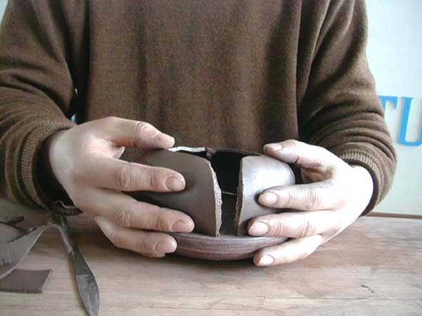7、将壶身底片正放于木转盘上，把四片已黏附稀泥之壶身泥片小心而准确的镶黏起来。