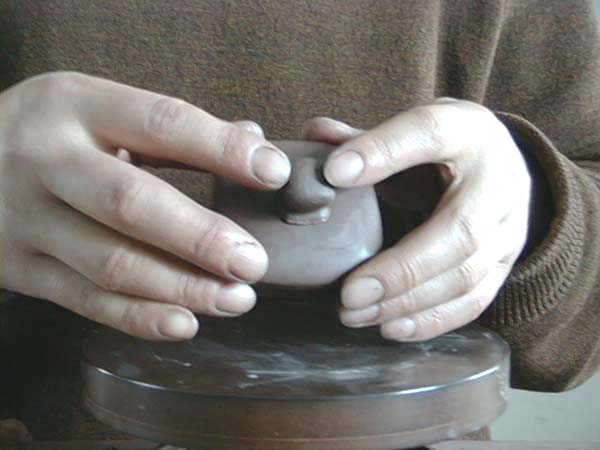 37、打修好壺鈕後，切下壺鈕，以稀泥黏貼於壺蓋正中，對正、壓緊。